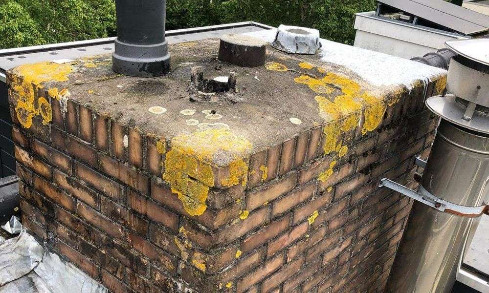 Bakstenen schoorsteen met mos en oude voegen